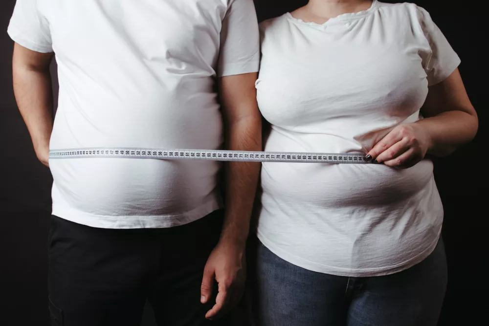 Overweight couple standing together wrapped with measure tape. Dieting, family weight loss and health care / Foto: Vadym Petrochenko