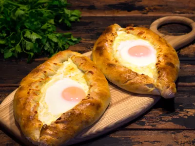 Georgian cuisine Adjarian khachapuri on a brown wooden background, caucasian cuisine, republic of Georgia / Foto: Andrey Lebedev
