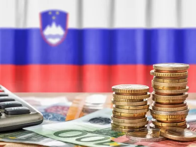 Euro banknotes and coins in front of the national flag of Slovenia / Foto: Zerbor