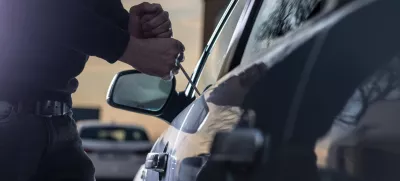 Auto thief in black balaclava trying to break into car with screwdriver. Car thief, car theft / Foto: Djedzura