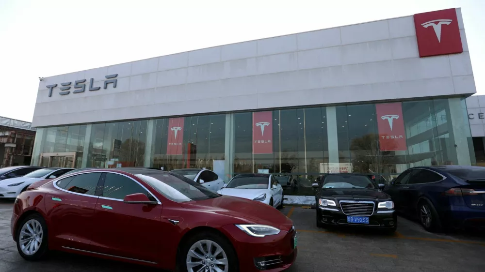 FILE PHOTO: A Tesla car is driven past a store of the electric vehicle maker in Beijing, China, January 4, 2024. REUTERS/Florence Lo/File Photo