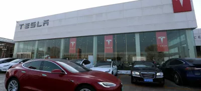 FILE PHOTO: A Tesla car is driven past a store of the electric vehicle maker in Beijing, China, January 4, 2024. REUTERS/Florence Lo/File Photo