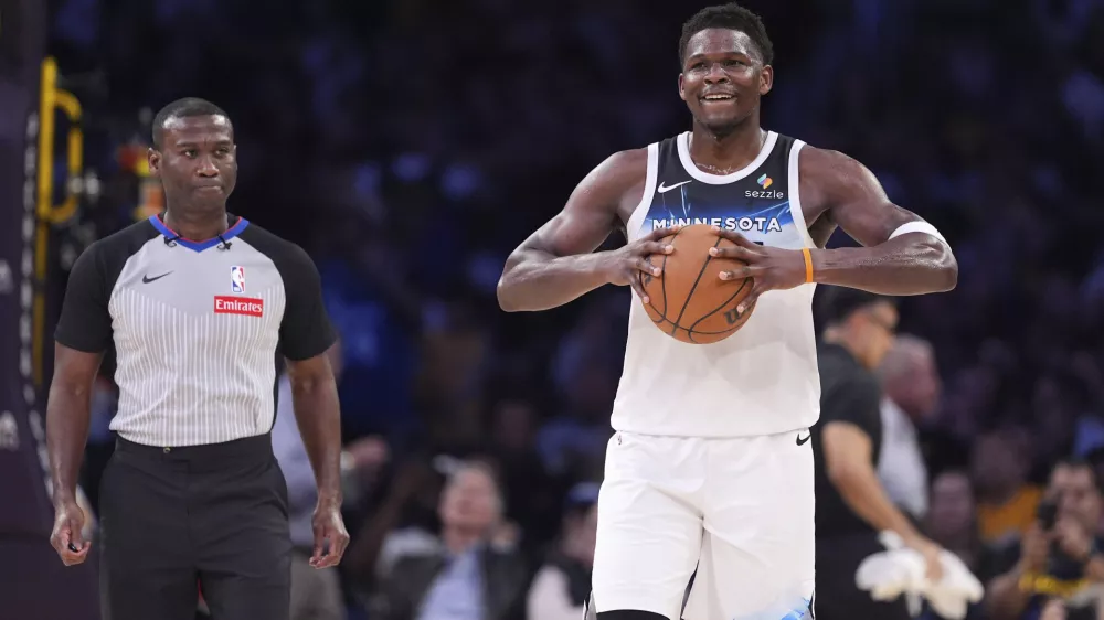 Minnesota Timberwolves guard Anthony Edwards holds the ball as a referee follows after he was ejected during the second half of an NBA basketball game against the Los Angeles Lakers, Thursday, Feb. 27, 2025, in Los Angeles. (AP Photo/Mark J. Terrill)
