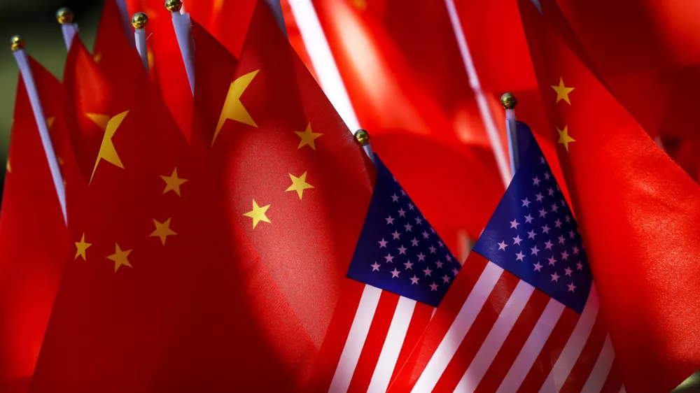 In this Sept. 16, 2018, photo, American flags are displayed together with Chinese flags on top of a trishaw in Beijing. The American Chamber of Commerce in China says Beijing will "dig its heels in" after U.S. tariff hikes and appealed for a negotiated end to their trade battle. The chamber on Tuesday, Sept. 18 warned a "downward spiral" appears certain after President Donald Trump approved a tariff hike on $200 billion of Chinese imports in a dispute over Beijing's technology policy. (AP Photo/Andy Wong)