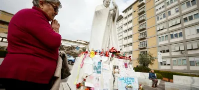 A woman prays near the statue of late Pope John Paul II outside Gemelli Hospital, where Pope Francis is admitted for treatment, in Rome, Italy, March 8, 2025. REUTERS/Vincenzo Livieri