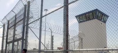 FILE - A correctional officer walks near a gate, which is one of two entrances into Kern Valley State Prison, June 14, 2005, in Delano, Calif. (AP Photo/Ric Francis,File)
