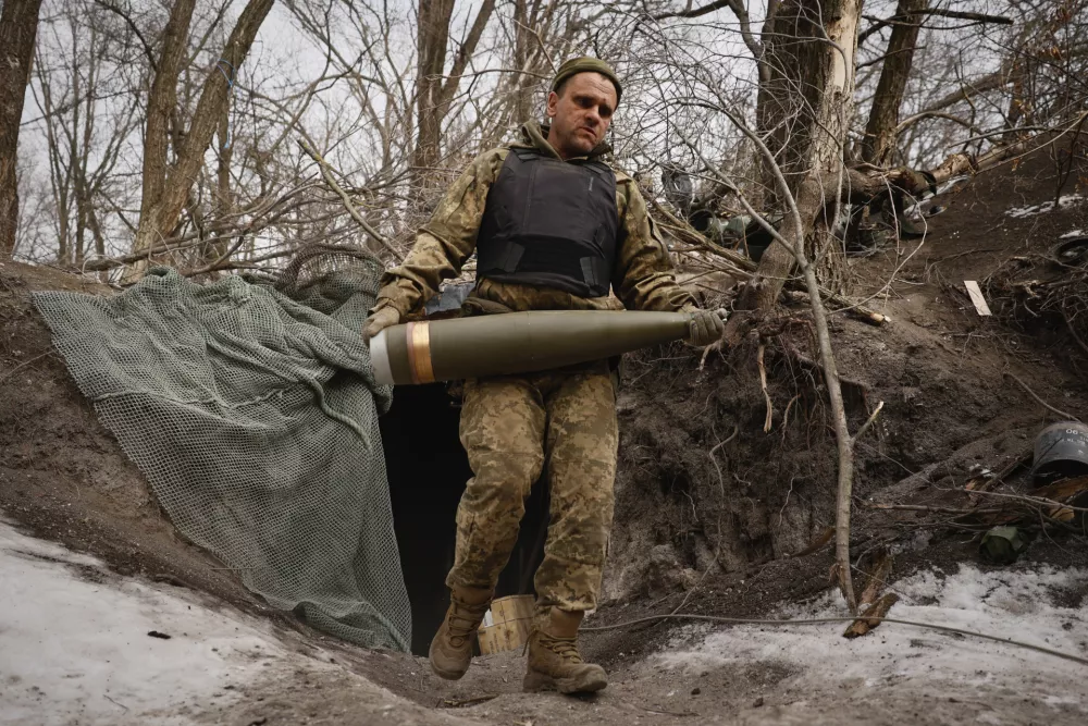 An Ukrainian serviceman carries a shell to fire a M777 howitzer towards Russian positions at the frontline near Donetsk, Ukraine, Sunday, March, 2, 2025. (AP Photo/Roman Chop)