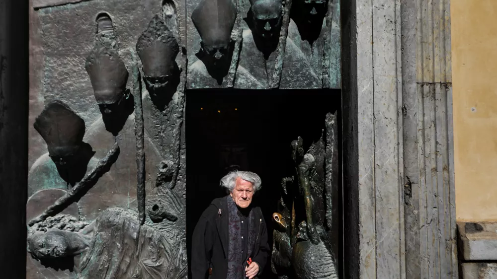 Dvainsedemdesetletni kipar Mirsad Begić pri stranskih vratih v ljubljansko stolnico, ki veljajo za tisto njegovo stvaritev, na katero je najbolj ponosen. Foto: Bojan Velikonja