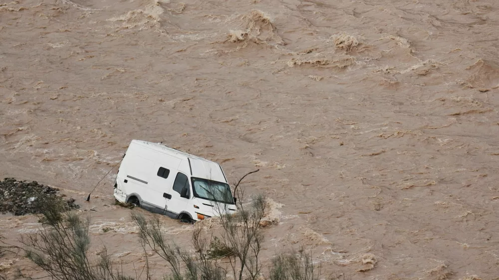 A van is photographed being swept away by the flood in Casasola, Malaga, Spain, Tuesday, March 18, 2025. (AP Photo/Gregorio Marrero)