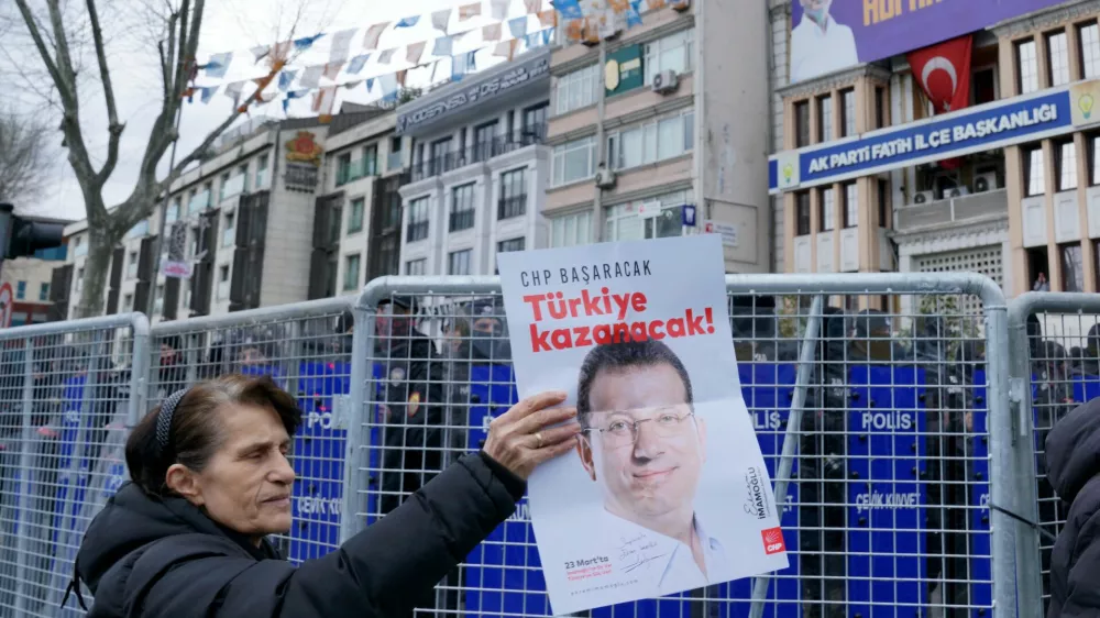 A woman holds a placard with the picture of Istanbul Mayor Ekrem Imamoglu as his supporters gather near the city's police headquarters in Istanbul, Turkey, March 19, 2025. REUTERS/Tolga Uluturk