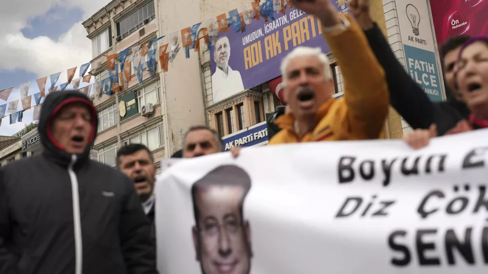Backdropped by a billboard featuring a photo of Turkey's President Recep Tayyip Erdogan, people chant slogans as they protest outside the Vatan Security Department, where Istanbul Mayor Ekrem Imamoglu is expected to be taken following his arrest in Istanbul, Turkey, Wednesday, March 19, 2025. (AP Photo/Francisco Seco)
