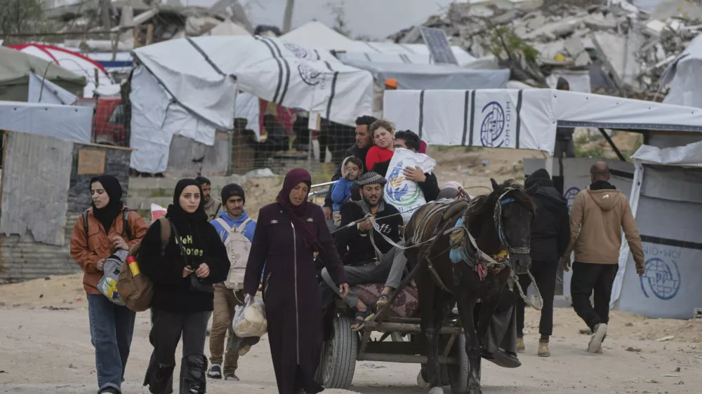Displaced Palestinians, carrying their belongings, move away from the areas where the Israeli army is operating after Israel's renewed offensive in the Gaza Strip, on the outskirts of Beit Lahia, Thursday, March 20, 2025. (AP Photo/Jehad Alshrafi)