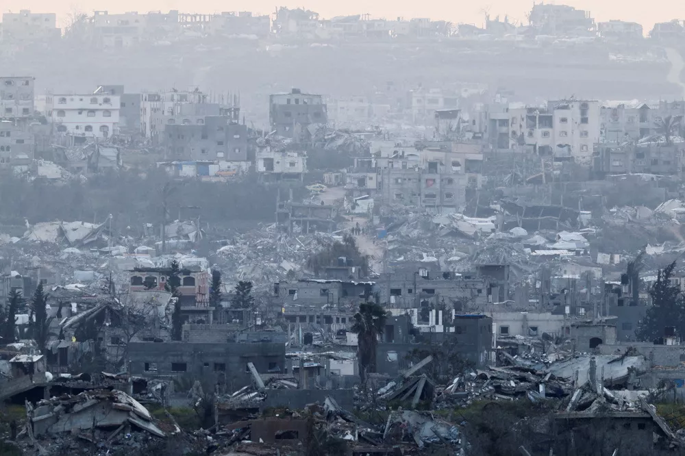 People walk among destroyed buildings in Gaza, as viewed from the Israel-Gaza border, March 20, 2025. REUTERS/Amir Cohen