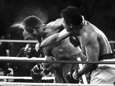 FILE - Perspiration flies from the head of George Foreman as he takes a right from challenger Muhammad Ali in the seventh round in the match dubbed Rumble in the Jungle in Kinshasa, Zaire, Oct. 30, 1974. (AP Photo/Ed Kolenovsky, File)