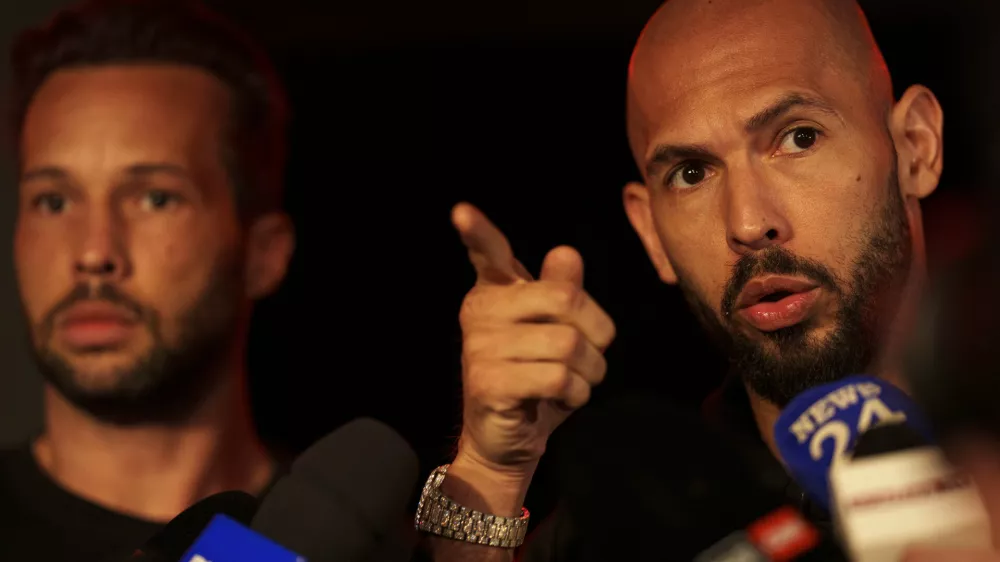 Andrew Tate, right, speaks to media next to his brother Tristan, after returning from the United States, outside his home on the outskirts of Bucharest, Romania, Saturday, March 22, 2025. (AP Photo/Vadim Ghirda)