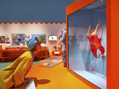 Guest curator Amber Butchart looks towards Pamela Anderson's Baywatch swimsuit on display at 'Splash! A century of Swimming and Style' an exhibition of swimwear and swim related items, at The Design Museum in London, Monday, March 24, 2025. (AP Photo/Kirsty Wigglesworth)