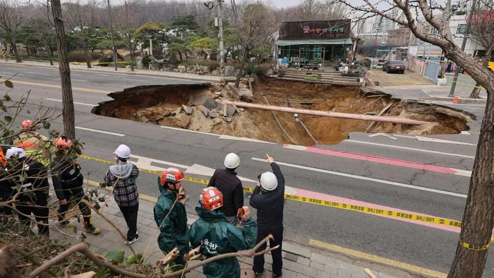 Rescue authorities inspect a sinkhole on an intersection in Seoul, South Korea, Tuesday, March 25, 2025. (Suh Dae-hyun/Yonhap via AP)