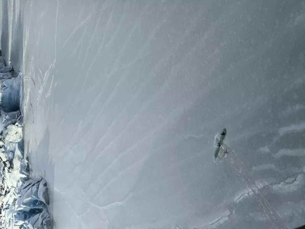 This photo provided Monday, March 24, 2025 by Dale Eicher shows an airplane partially submerged into the ice of Tustumena Lake near Soldotna, Alaska, with the three survivors standing on the plane's wing. (Dale Eicher via AP)