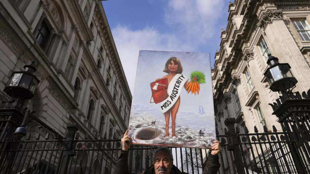 Artist Kaya Mar holds a painting depicting Chancellor Rachel Reeves at the entrance gate to Downing Street in London, Wednesday, March 26, 2025. (AP Photo/Kirsty Wigglesworth)