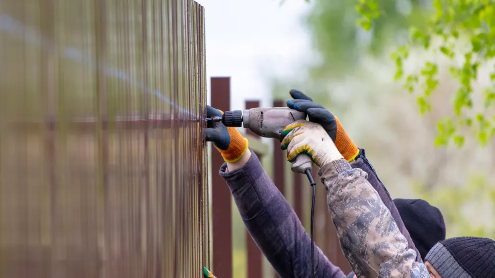 Workers install a metal profile fence. / Foto: Schankz