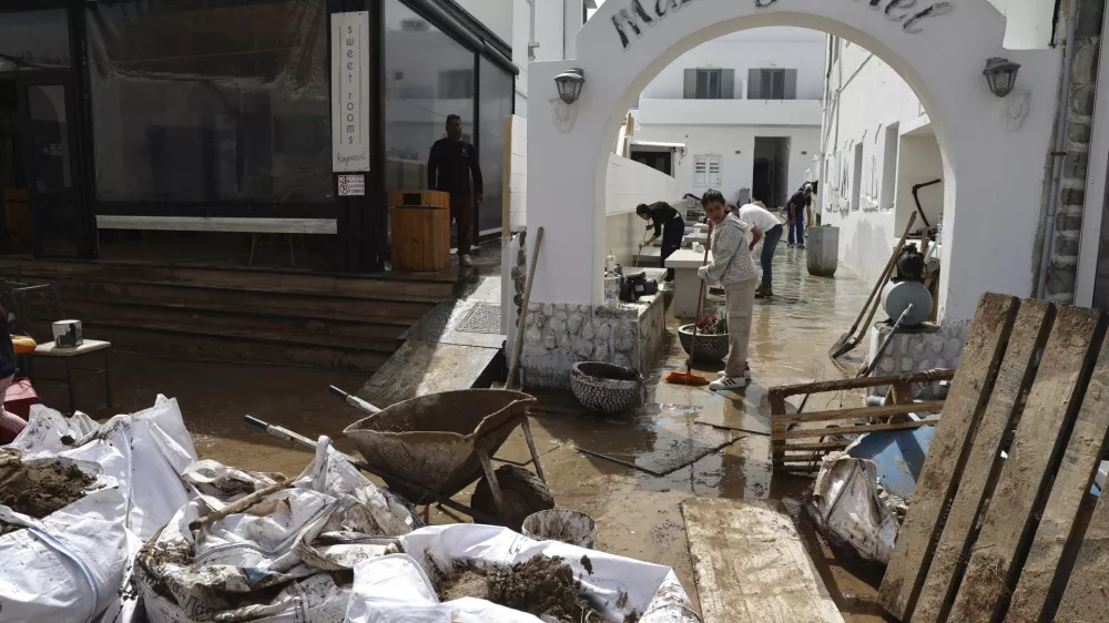 People try to clear the mud from a hotel after a powerful storm which has triggered widespread flooding at the port of Naousa, on the Aegean Sea island of Paros, Greece, Tuesday, April 1, 2025. (John Liakos/InTime News via AP)