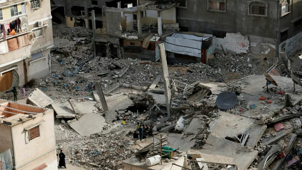 FILE PHOTO: A Palestinian woman walks near the rubble of houses, in Khan Younis in the southern Gaza Strip March 29, 2025. REUTERS/Hatem Khaled/File Photo