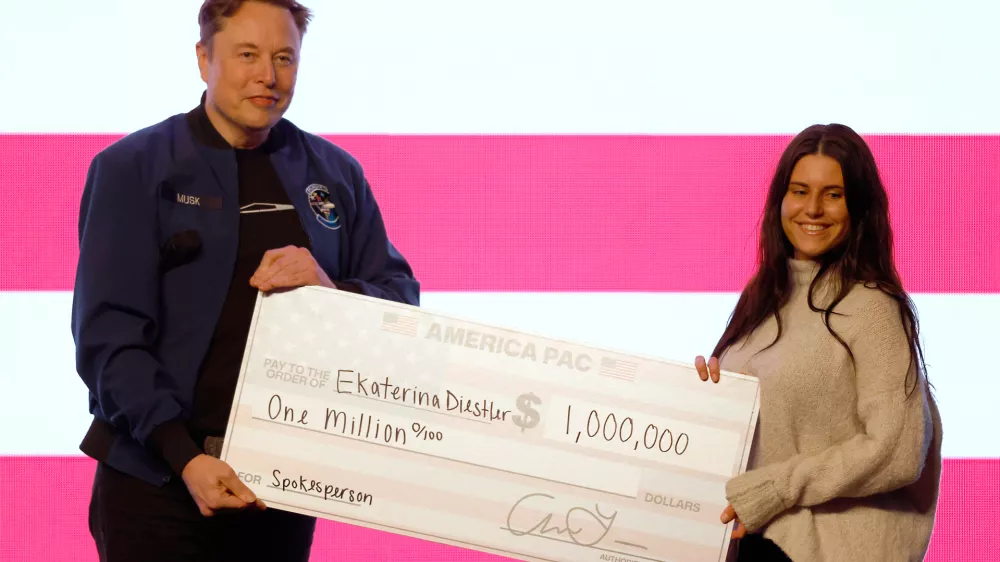 Elon Musk presents a check for $1 million dollars during a town hall Sunday, March 30, 2025, in Green Bay, Wis. (AP Photo/Jeffrey Phelps)