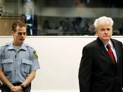 Former Yugoslav President Slobodan Milosevic (R) enters the courtroom for the start of his defence case at the Yugoslav war crimes tribunal in the Hague, July 5, 2004. Milosevic appeared at tribunal on Monday but the start of his defence was in doubt with a judge raising concerns about the defendant's health.  REUTERS/Bas Czerwinski/Pool