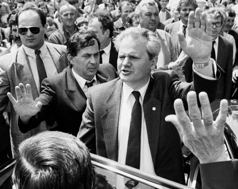 Former Yugoslav President Slobodan Milosevic (R) waves to a crowd accompanied by his bodyguard (L) and Mihalj Kertes (C) during a visit to Serbia's province of Vojvodina in this 1988 file photo. Police on Friday detained Mihalj Kertes, a close ally of ousted president Slobodan Milosevic, on suspicion of fraud involving millions of dollars, the Serbian interior ministry said. It was the first arrest of a senior figure in the Milosevic administration, whose decade in power was marked by conflict, economic mismanagement, and sanctions which fuelled smuggling. The ministry said Mihalj Kertes, former head of Yugoslav customs, was s`uspected of having deprived the Yugoslav government budget of four million German marks ($1.84 million) and of 40 million dinars ($597,000 at the current rate) through abuse of power. PICTURE TAKEN MARCH 1988.IM/