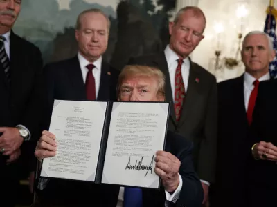 President Donald Trump displays signs a presidential memorandum imposing tariffs and investment restrictions on China in the Diplomatic Reception Room of the White House, Thursday, March 22, 2018, in Washington. (AP Photo/Evan Vucci)
