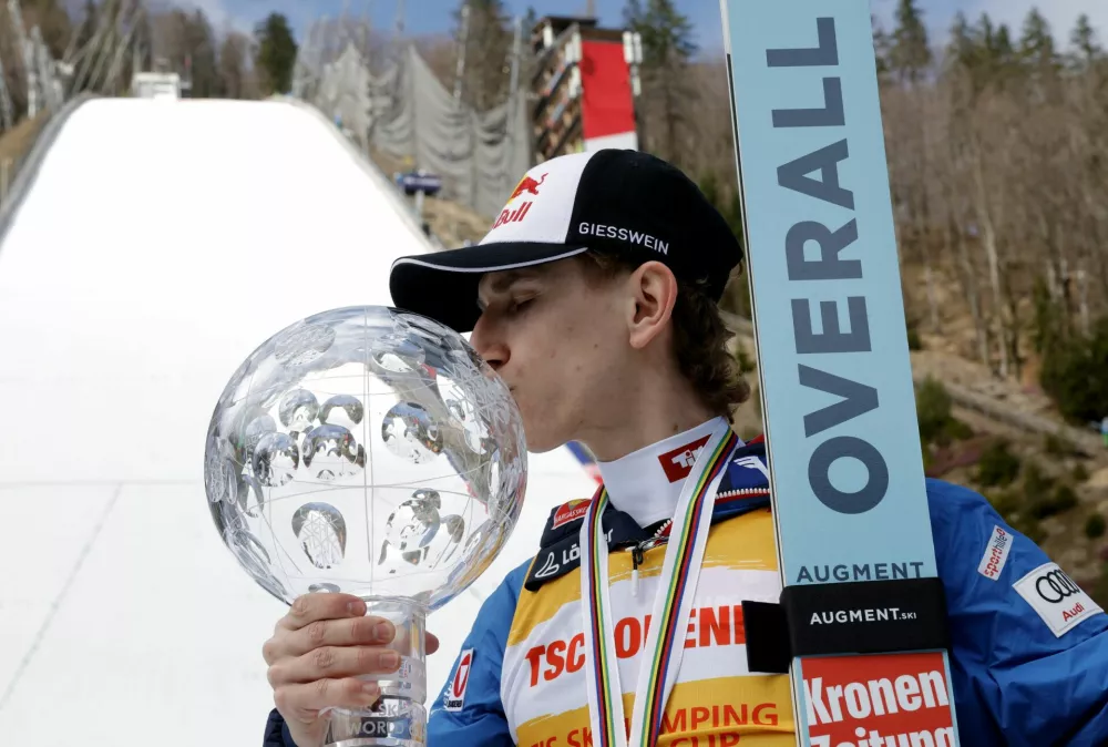 Ski Jumping - FIS Ski Jumping World Cup - Planica, Slovenia - March 30, 2025 Austria's Daniel Tschofenig kisses a trophy after finishing as the overall winner of the FIS Ski Jumping World Cup REUTERS/Borut Zivulovic