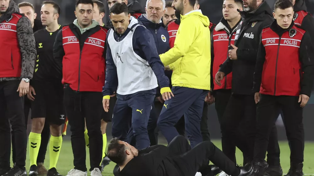 Galatasaray's coach Okan Buruk, bottom, lies on the ground after Fenerbahce's manager Jose Mourinho, center, grabbed his nose at the end of the Turkish Cup quarterfinals soccer match between Fenerbahce and Galatasaray at the Ulker stadium, in Istanbul, Wednesday, April 2, 2025. (Murat Akbas/Dia Photo via AP)