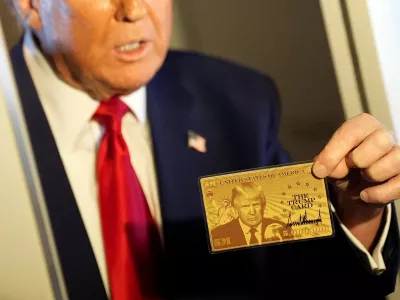 U.S. President Donald Trump holds "The Trump Card" as he speaks with journalists onboard Air Force One en route to Miami, Florida, U.S., April 3, 2025. REUTERS/Kent Nishimura