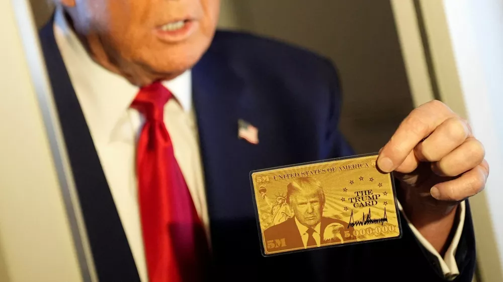 U.S. President Donald Trump holds "The Trump Card" as he speaks with journalists onboard Air Force One en route to Miami, Florida, U.S., April 3, 2025. REUTERS/Kent Nishimura