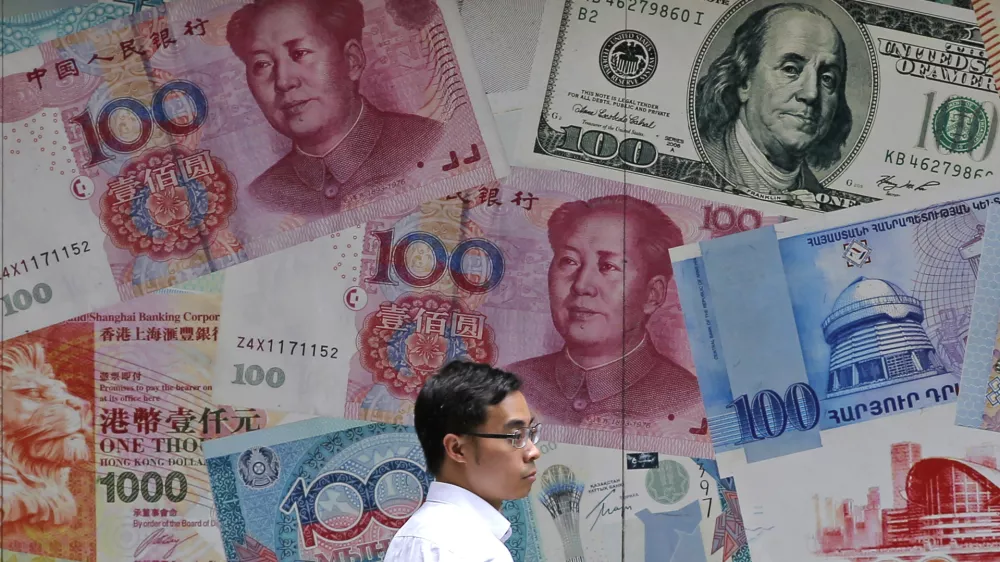 FILE - In this June 10, 2019, file photo, a man walks past a money exchange shop decorated with different banknotes at Central, a business district of Hong Kong. China's yuan fell Friday, Aug. 2, 2019, to its lowest level of the year against the dollar following U.S. President Donald Trump's threat of new tariffs on Chinese goods, coming close to breaking the politically sensitive level of seven to the U.S. currency. (AP Photo/Kin Cheung, File)