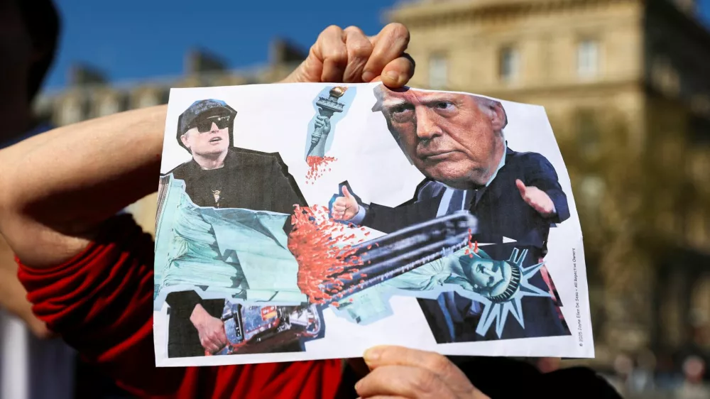 A person holds a placard as people attend 'Hands Off!' demonstration against U.S. President Donald Trump and his adviser Elon Musk as part of an anti-Trump and anti-Tesla worldwide movement, at Place de la Republique in Paris, France, April 5, 2025. REUTERS/Abdul Saboor