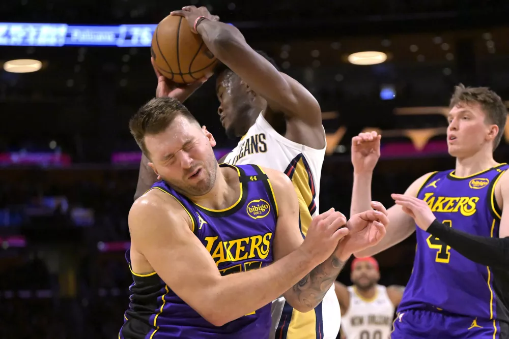 Apr 4, 2025; Los Angeles, California, USA; Los Angeles Lakers guard Luka Doncic (77) reacts after getting an elbow in the face as he is defending New Orleans Pelicans center Yves Missi (21) in the second half at Crypto.com Arena. Mandatory Credit: Jayne Kamin-Oncea-Imagn Images