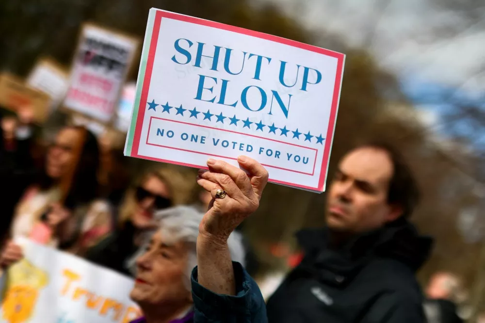 A demonstrator holds a sign as members and supporters of "Democrats Abroad" call on fellow Americans living in Germany to protest for "an end of the chaos" at home and against U.S. President Donald Trump and his adviser Elon Musk in Berlin, Germany, April 5, 2025. REUTERS/Christian Mang