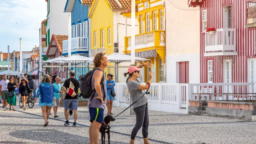 Tourists take photos of typical multicolored striped houses in Costa Nova, Aveiro, Portugal. COSTA NOVA, PORTUGAL - August 19, 2019.