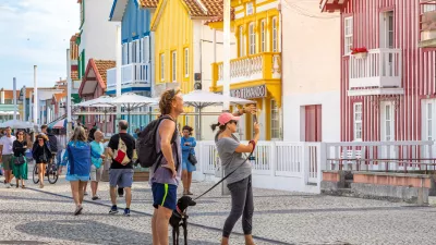 Tourists take photos of typical multicolored striped houses in Costa Nova, Aveiro, Portugal. COSTA NOVA, PORTUGAL - August 19, 2019.