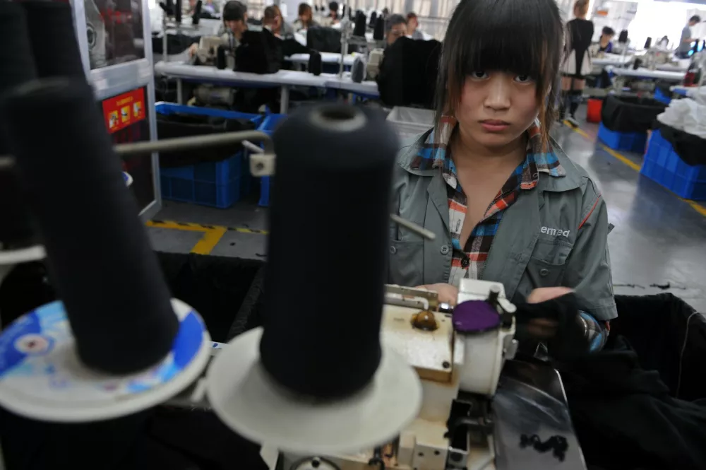 A college student looks up as she works at a garment factory in Jiaxing, Zhejiang province, October 19, 2012. More and more factories in China move inland from higher-cost coastal manufacturing centers, labor is turning out to be neither as cheap nor abundant as many companies believed. As a result, many multinationals and their suppliers are corralling millions of teenage vocational students to work long hours doing assembly line jobs that might otherwise go unfilled - jobs that the students have no choice but to accept. Picture taken October 19, 2012. REUTERS/Stringer (CHINA - Tags: BUSINESS) CHINA OUT. NO COMMERCIAL OR EDITORIAL SALES IN CHINA