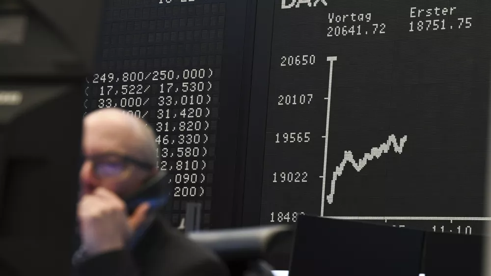 While a stock exchange trader sits in front of his monitors on the trading floor of the Frankfurt Stock Exchange, Germany, the display board with the Dax curve shows a value of less than 20,000 points. (Arne Dedert/dpa via AP)