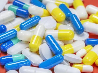 Colored pills, pills and capsules on a red background / Foto: Okskaz