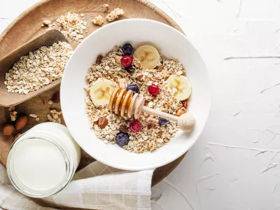 A bowl of dry granola and muesli served with fresh fruit and nuts. Traditional Oatmeal plate. Healthy food, diet. Top view. / Foto: Dulezidar