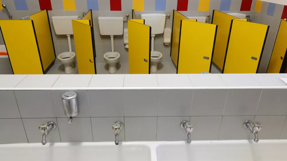 long sink with four taps inside a kindergarten with toilets with yellow doors without children / Foto: Chiccododifc