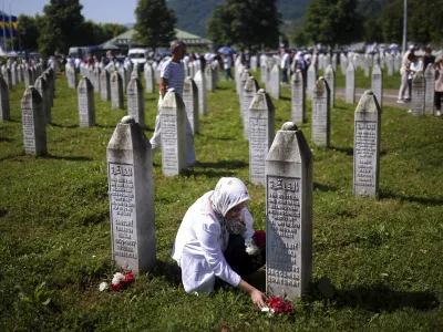 A Bosnian muslim woman lays flowers at the grave of her relative, victim of the Srebrenica genocide, at the Srebrenica Memorial Centre, in Potocari, Bosnia, Thursday, July 11, 2024. Thousands gather in the eastern Bosnian town of Srebrenica to commemorate the 29th anniversary on Monday of Europe's only acknowledged genocide since World War II. (AP Photo/Armin Durgut)