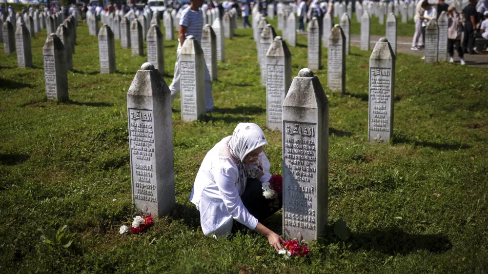 A Bosnian muslim woman lays flowers at the grave of her relative, victim of the Srebrenica genocide, at the Srebrenica Memorial Centre, in Potocari, Bosnia, Thursday, July 11, 2024. Thousands gather in the eastern Bosnian town of Srebrenica to commemorate the 29th anniversary on Monday of Europe's only acknowledged genocide since World War II. (AP Photo/Armin Durgut)