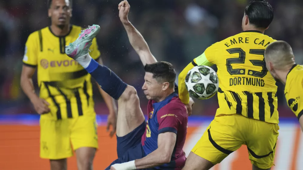 Barcelona's Robert Lewandowski, center, attempts a shot at goal in front of Dortmund's Emre Can during the Champions League quarterfinal first leg soccer match between Barcelona and Borussia Dortmund, at the Lluis Companys Olympic stadium in Barcelona, Spain, Wednesday, April 9, 2025. (AP Photo/Emilio Morenatti)