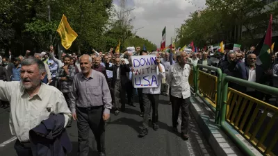 A demonstrator carries an anti-U.S. placard in an anti-Israeli rally after the Friday prayer in Tehran, Iran, Friday, April 11, 2025. (AP Photo/Vahid Salemi)
