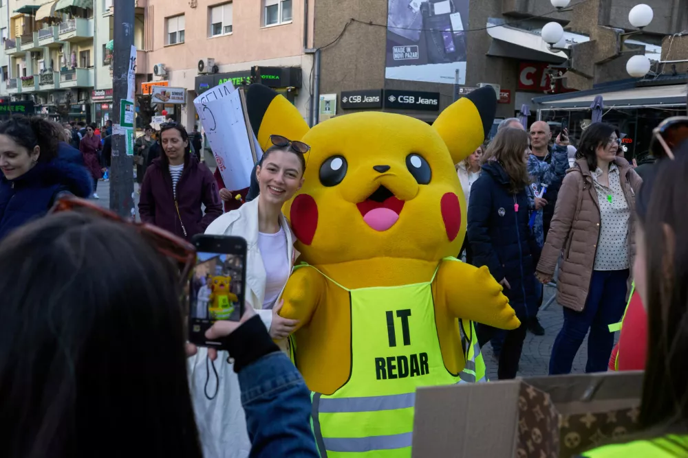 A person dressed in a Pikachu costume poses for photographs with people during an anti-corruption protest led by university students in the southwestern town of Novi Pazar, Serbia, Saturday, April 12, 2025. (AP Photo/Marko Drobnjakovic)